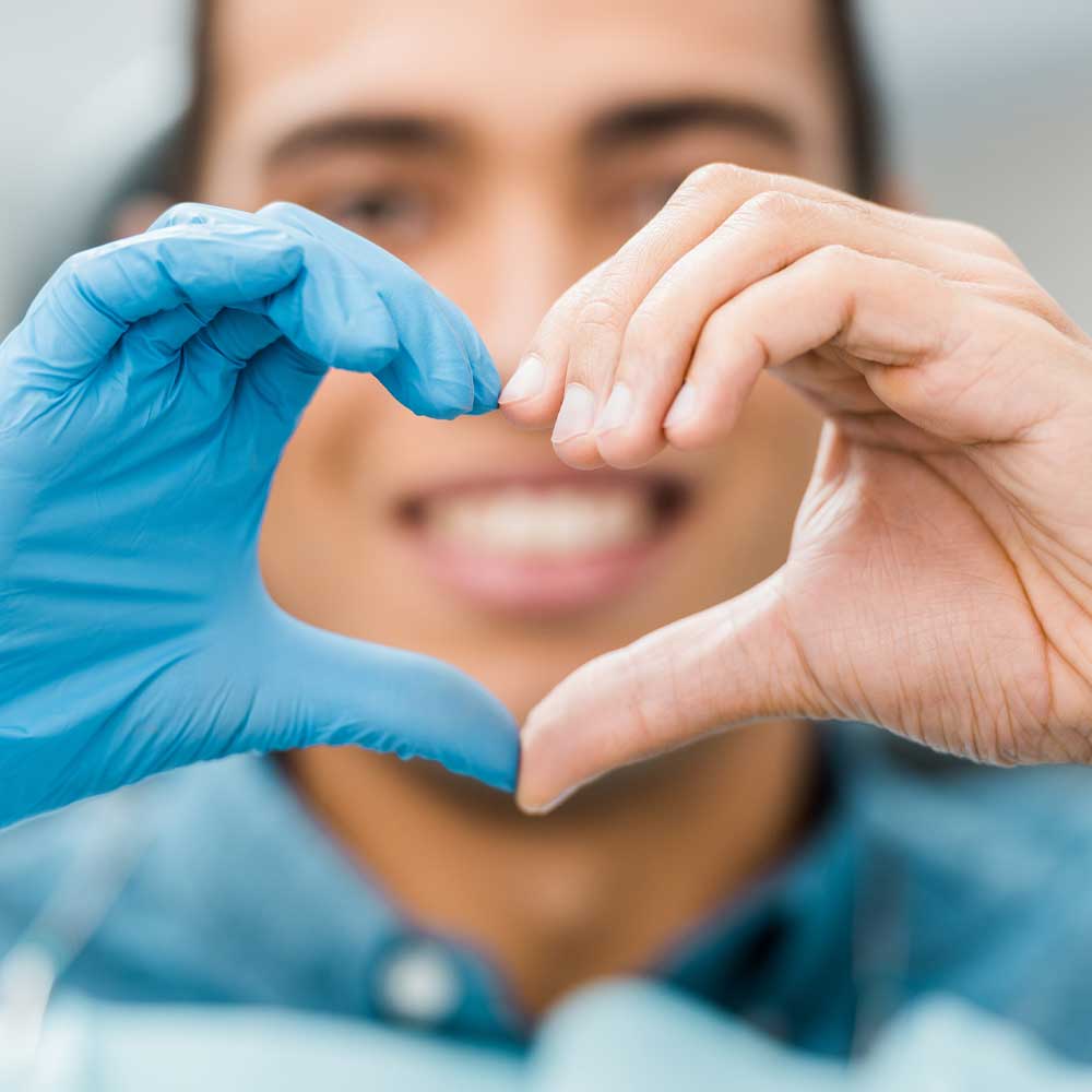 man at dentist make heart shape with hands